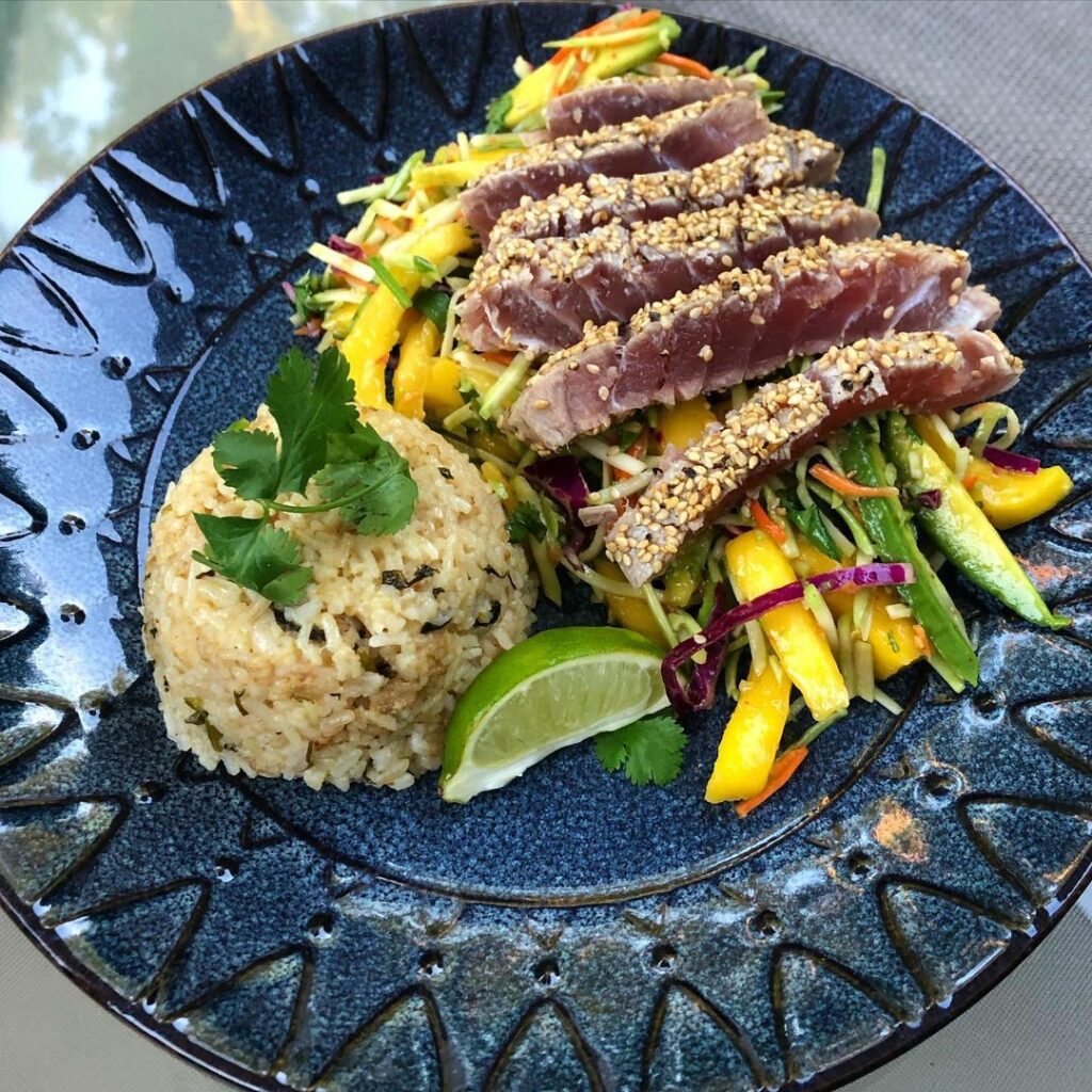 Sesame encrusted rare ahi tuna steaks over mango avocado broccoli slaw and cilan…